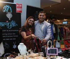 A man and a woman are standing in front of a table with jewelry on it.