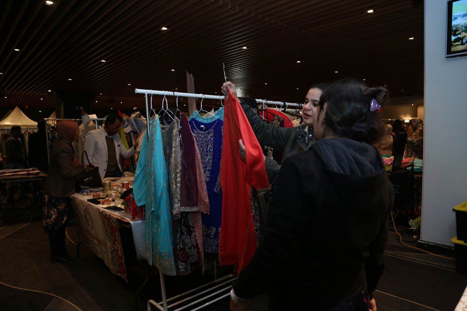 Two women are looking at clothes on a rack at a market.