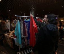 Two women are looking at clothes on a rack at a market.