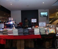 A man is standing behind a table full of books.