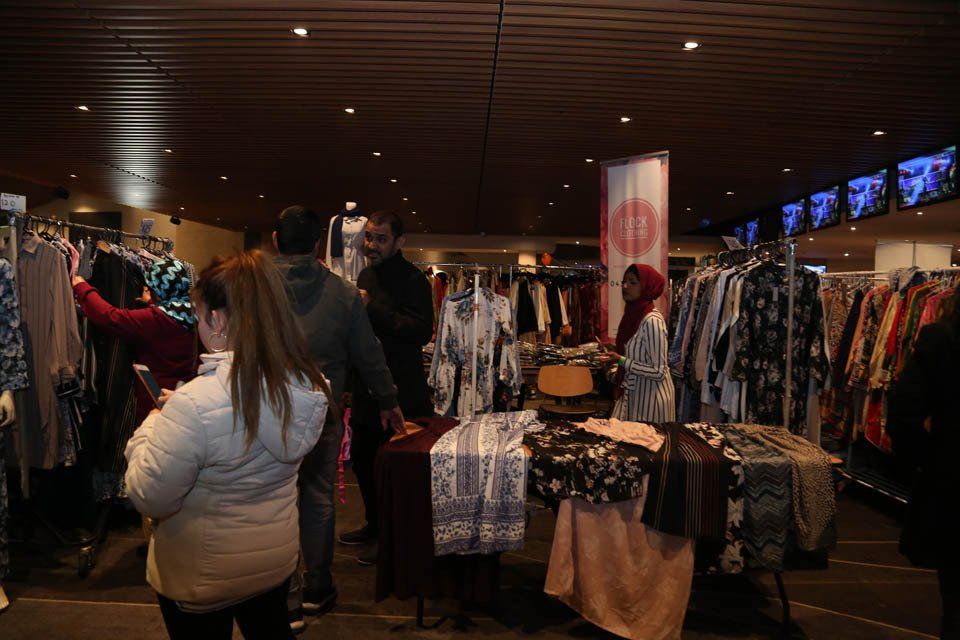 A group of people are standing in a store looking at clothes.