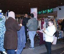 A group of people are standing in a store looking at clothes.