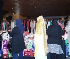 A group of women are standing in front of a display of clothes.