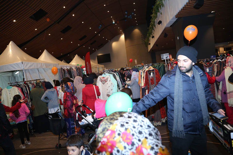 A man is standing in front of a crowd of people at a clothing store.