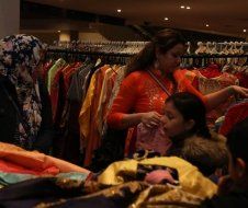 A woman is standing in front of a rack of clothes in a store.
