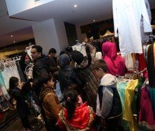 A group of people are standing in a store looking at clothes.