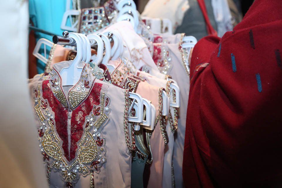 A woman is looking at a row of clothes hanging on a rack.