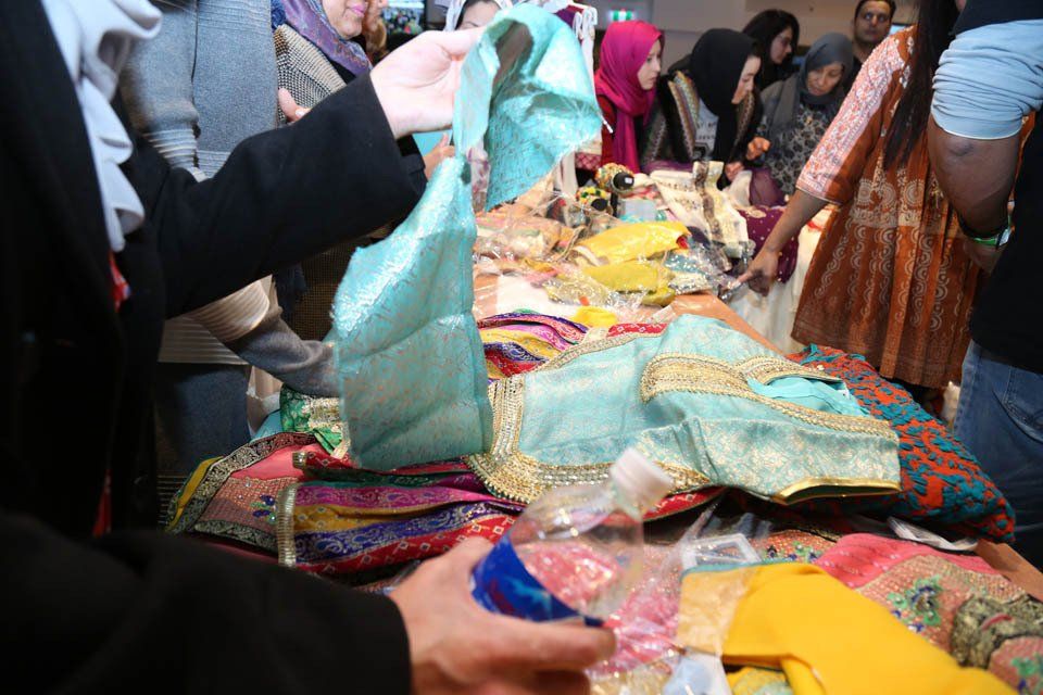 A group of people are gathered around a table looking at clothes.