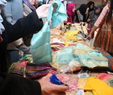 A group of people are standing around a table looking at clothes.