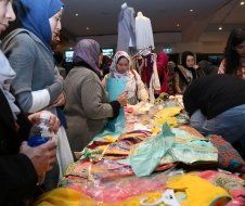 A group of people are standing around a table with clothes on it.