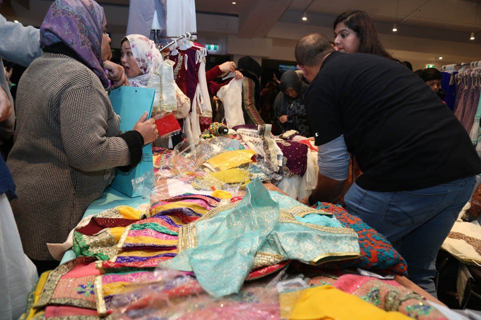 A group of people are standing around a table with clothes on it.