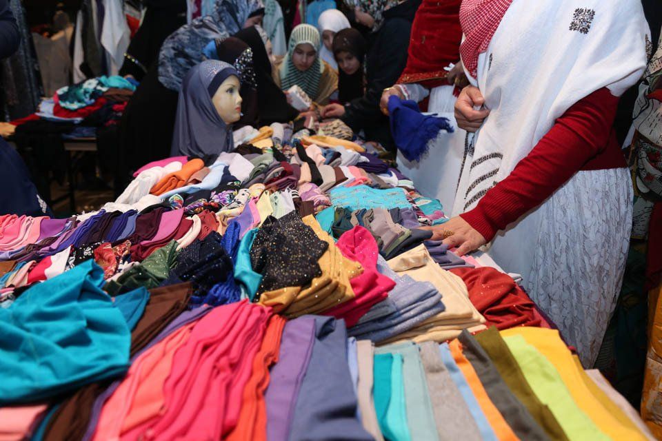 A group of women are standing around a table full of clothes.