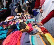 A woman is standing in front of a table full of clothes.