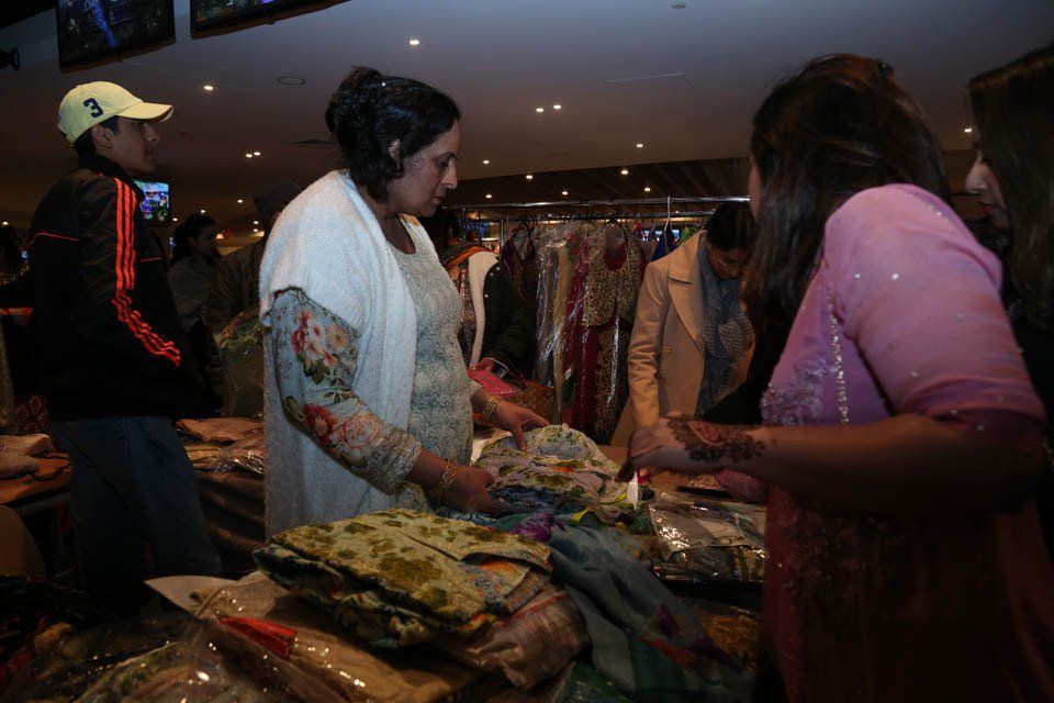 A group of people are standing around a table looking at clothes.