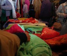 A group of people are standing around a table with lots of colorful fabrics.
