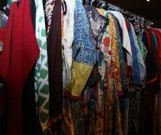 A bunch of clothes are hanging on a rack in a closet.