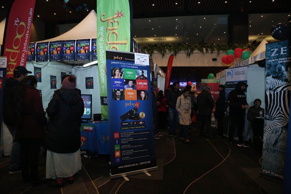 A group of people are standing around a booth at a convention.