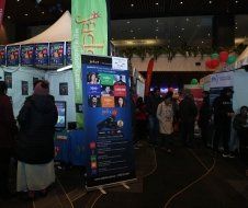 A group of people are standing around a booth at a convention.
