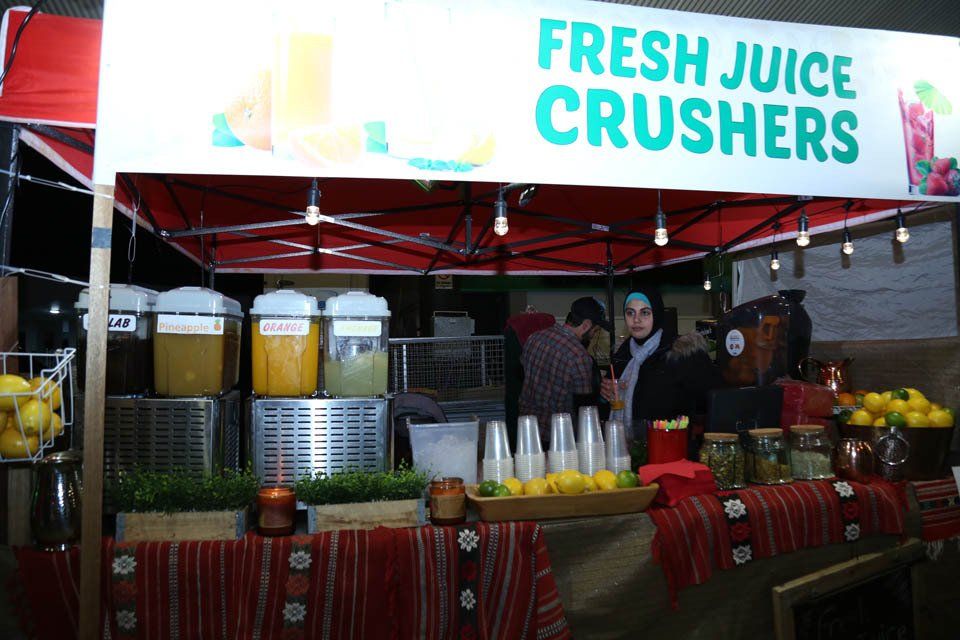A woman stands behind a fresh juice crushers stand