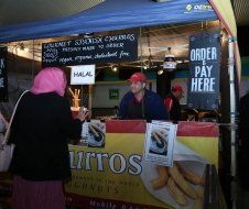 A woman is standing in front of a churros stand.