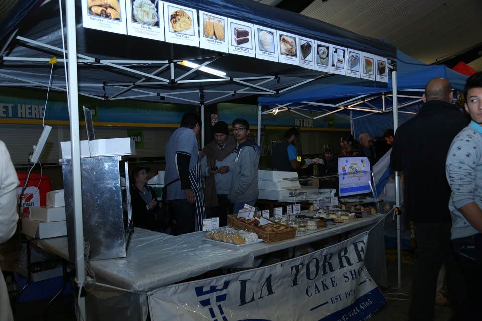 A group of people are standing around a food stand called la torre