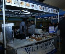 A group of people are standing around a table under a tent.