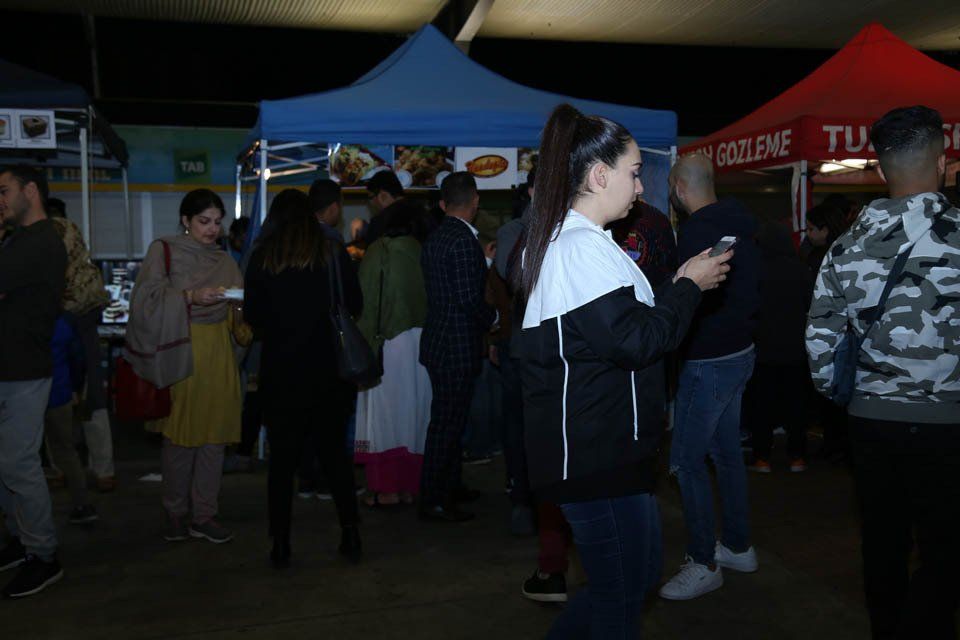 A group of people are standing in front of a food stand.