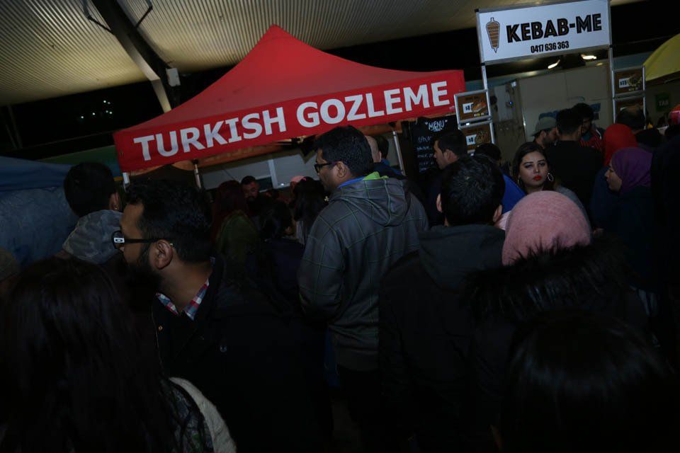 A crowd of people are gathered under a tent that says turkish gozleme