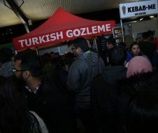 A group of people are standing under a tent that says turkish gozleme.