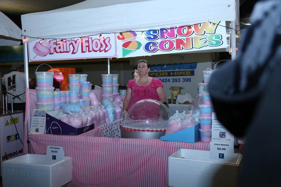 A woman is selling cotton candy at a carnival.