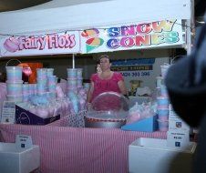 A woman is selling cotton candy at a carnival.