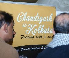 Two men are looking at a sign that says chandigarh to kolkata feeding with a smile