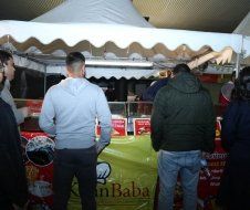 A group of people are standing in front of a food stand.