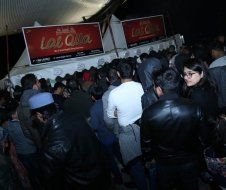 A crowd of people are standing in front of a sign that says las ollas.