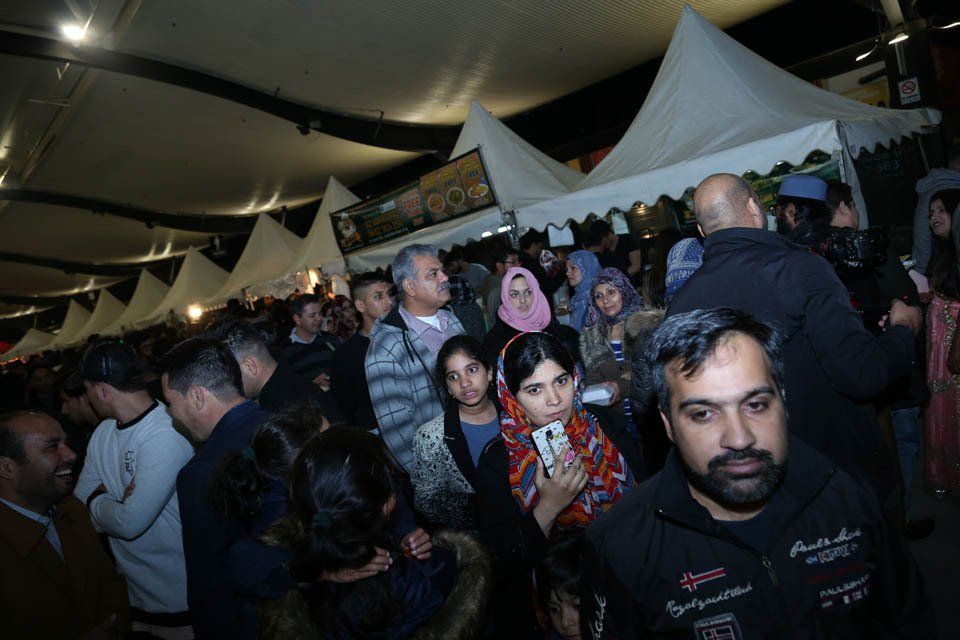 A crowd of people are gathered under tents at a festival.
