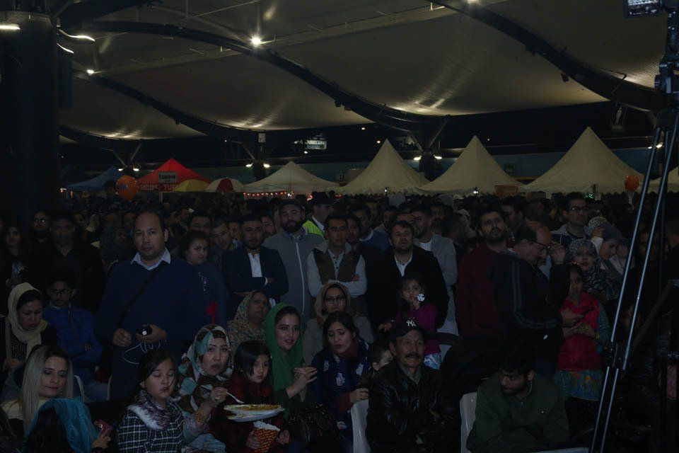 A crowd of people are gathered under a tent at night