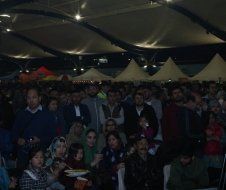 A large group of people are sitting under a tent.