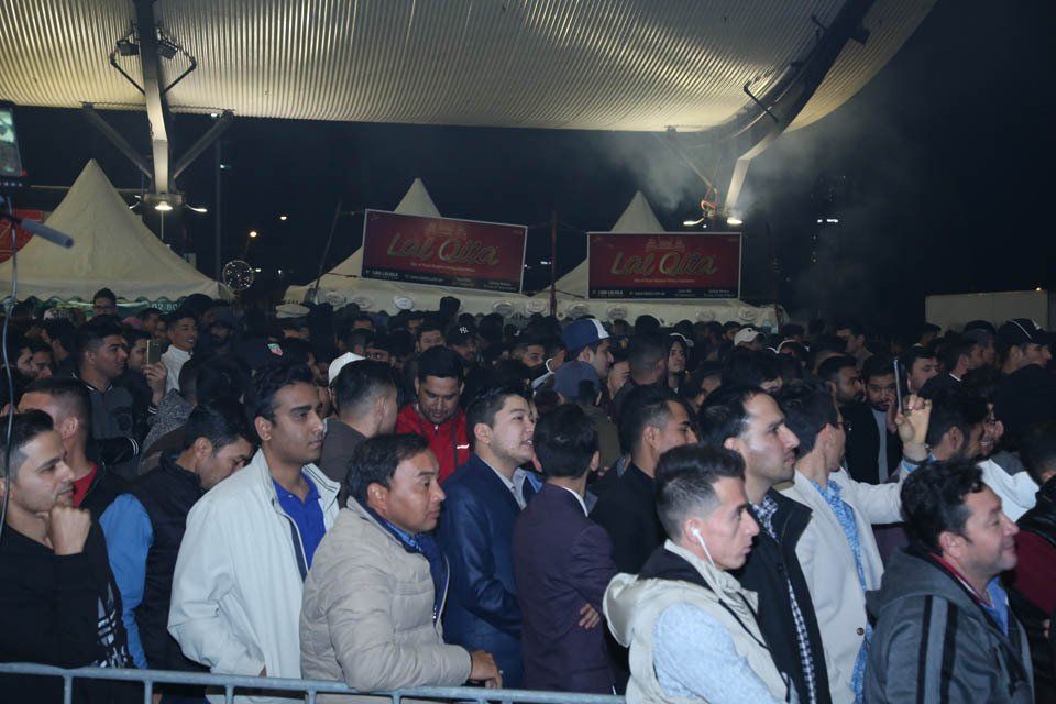 A crowd of people standing in front of a coca cola sign