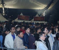 A crowd of people standing in front of a coca cola sign