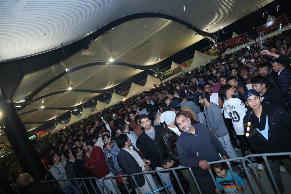 A crowd of people are standing in a stadium with a man wearing a jersey with the number 19 on it