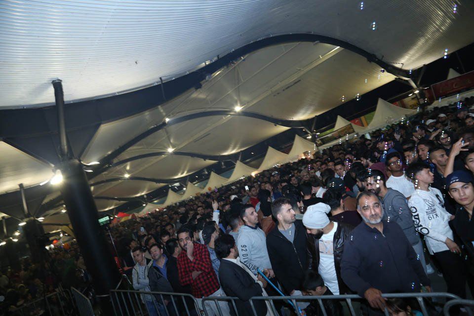 A crowd of people are standing under a canopy.