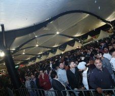 A crowd of people are standing in a stadium under a tent.