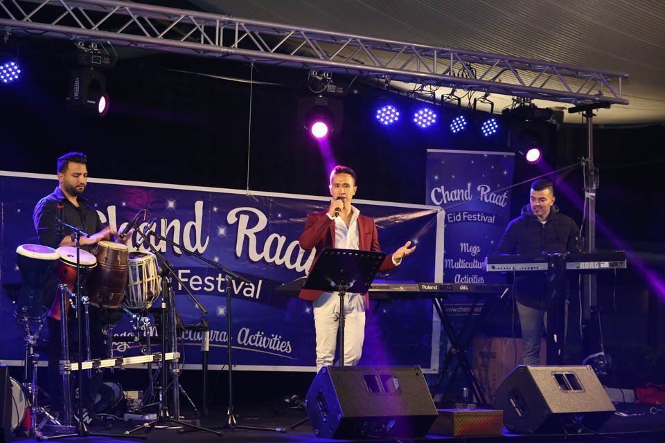 A woman is singing into a microphone on a stage in front of a band.