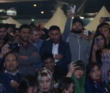 A group of people are standing in a crowd taking pictures with their phones.