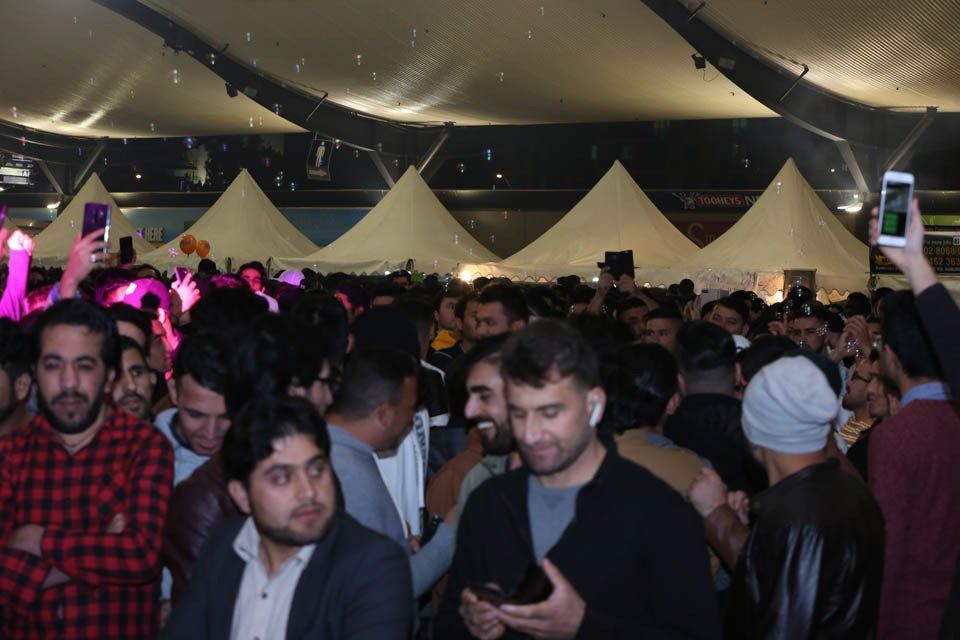 A crowd of people are gathered under a tent at a party