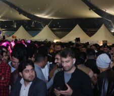 A crowd of people are gathered under a tent at night.
