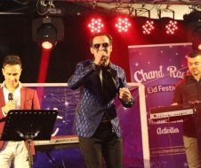 A man in a suit is singing into a microphone on a stage.