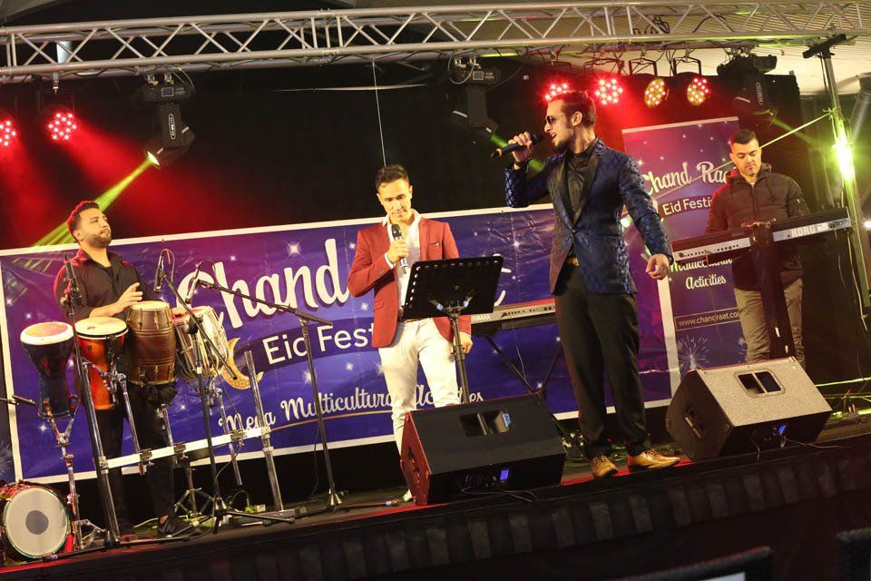 A group of men are standing on a stage in front of a sign that says grand