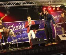 A group of men are standing on a stage playing instruments and singing into microphones.