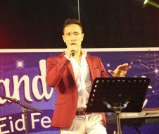 A man in a red jacket is singing into a microphone.